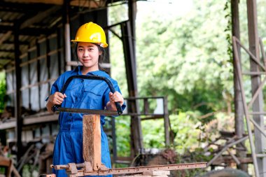 Asyalı teknisyen kız işyerinde demir testeresi ile çalışıyor..