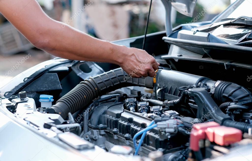 Hands of automotive mechanic check and inspecting the engine of the car.