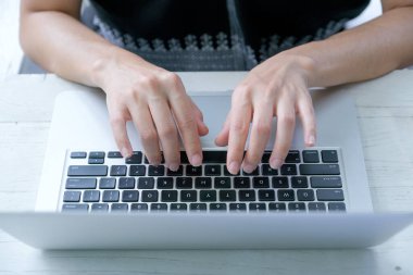 Kapalı eller dizüstü bilgisayarın klavyesine gün ışığı ile yazı yazıyorlar. İletişim kurmak ve işlerini motive etmek için teknoloji teçhizatıyla çalışma kavramı.