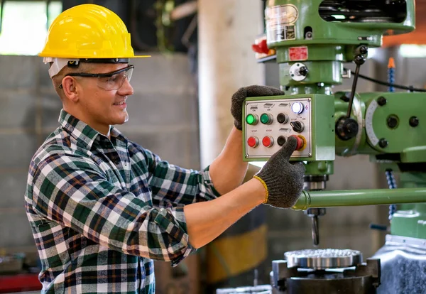 Factory worker man stand and press button of the machine to work in workplace also look happy by smiling. Concept of good management system for industrial business.