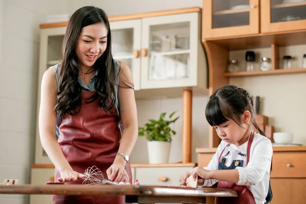 Asyalı anne ve kız gün ışığında mutfakta birlikte kil modelleme oynuyorlar ve mutlu görünüyorlar. Evlerinde farklı yaşlarda olan aile zamanlarının tadını çıkarma kavramı.