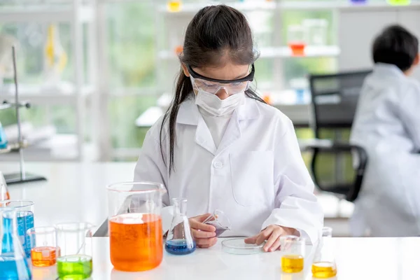 可爱的小女孩喜欢在实验室里用白光检查这种色素化学物 为儿童提供的良好做法和科学教育概念支持了他们的学习 — 图库照片