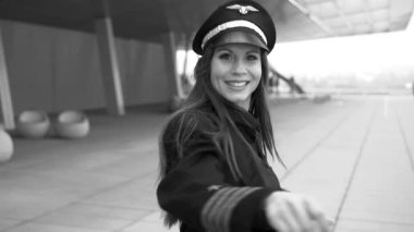 Güzel kadın pilot havaalanında yürüyor ve dans ediyor. Siyah beyaz ton