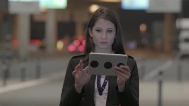 Genç beyaz kadın geceleri tablet bilgisayar kullanıyor.