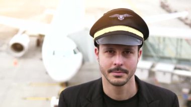 Genç erkek pilot havaalanında poz veriyor.