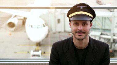 Genç erkek pilot havaalanında poz veriyor.
