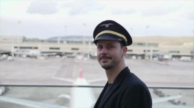 Genç erkek pilot havaalanında yürüyor.