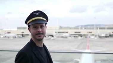 Genç erkek pilot havaalanında yürüyor.