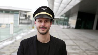 Genç erkek pilot havaalanında yürüyor.