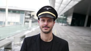 Genç erkek pilot havaalanında yürüyor.