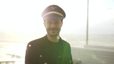 Genç erkek pilot, karlı havada havaalanında poz veriyor.