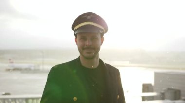 Genç erkek pilot, karlı havada havaalanında poz veriyor.