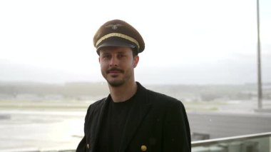 Genç erkek pilot karlı havada havaalanında yürüyor.