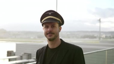Genç erkek pilot karlı havada havaalanında yürüyor.