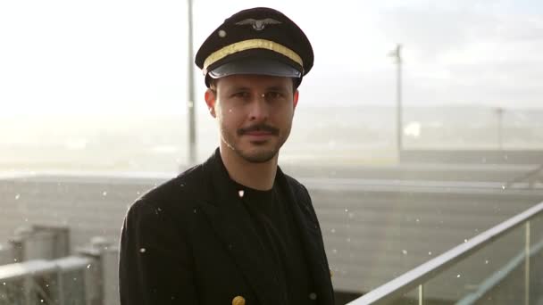 若い男性パイロットは雪の日に空港でポーズをとっています — ストック動画