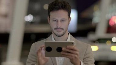 Genç beyaz adam şehirde tablet bilgisayar kullanıyor.