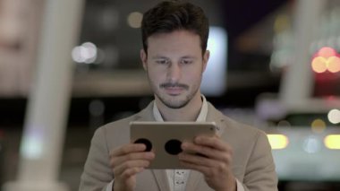 Genç beyaz adam şehirde tablet bilgisayar kullanıyor.