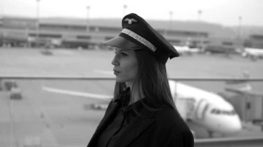 Güzel kadın pilot havaalanında yürüyor. Siyah beyaz ton