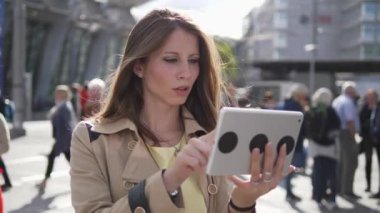 Beyaz bir kadın şehir bölgesinde tablet tablet kullanıyor.