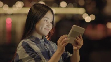 Genç Asyalı kadın geceleri tablet kullanıyor. 