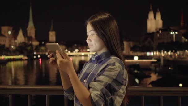 在城市里 年轻的亚洲女人站在河边时 晚上用平板Pc — 图库视频影像