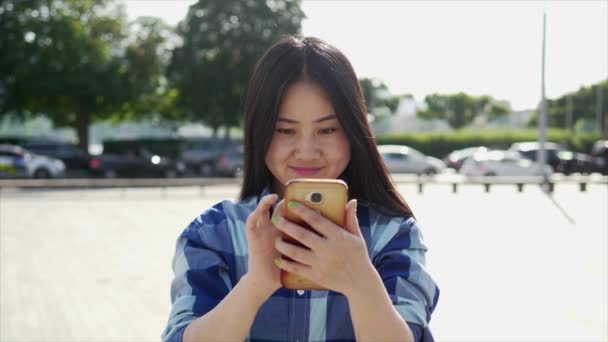 若いアジアの女性は 市内に立っている間に携帯電話を使用している — ストック動画