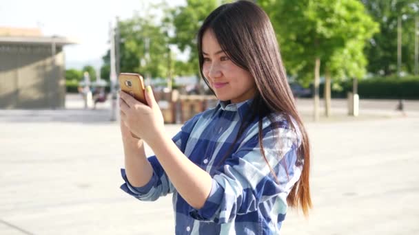 若いアジアの女性は 市内に立っている間に携帯電話を使用している — ストック動画