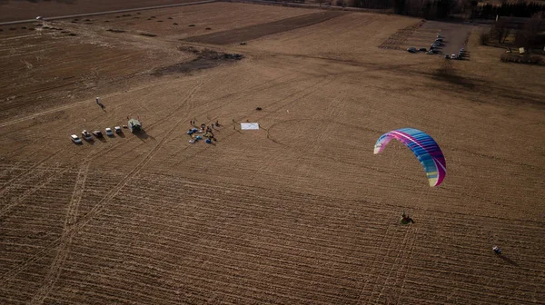 Paraglider flies over fields. High altitude. The athlete turns the thermal current. Rise up. Weather for flights. Top view of the paraglider flying over a green field with a road. Satisfaction. — Stock Photo, Image