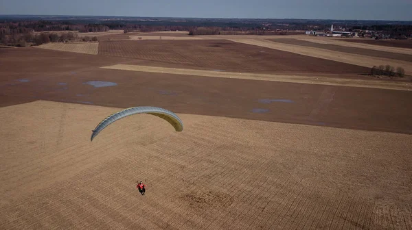 Yamaçparaşütü tarlalara uçar. Yüksek irtifa. Atlet termal geçerli döner. Yükselin. Hava uçuş için. Bir yol ile yeşil bir alan üzerinde uçan yamaçparaşütü üstten görünüm. Memnuniyeti.