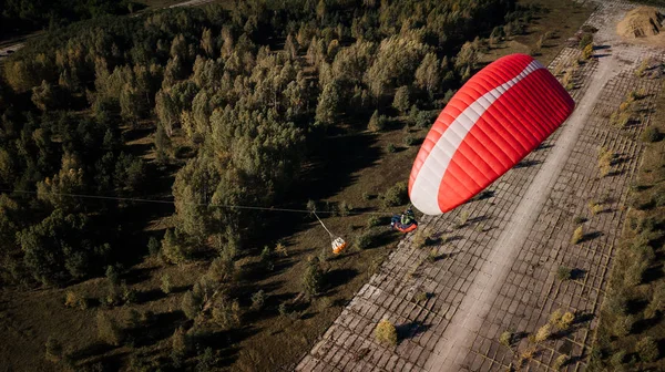 Paraglider flies over fields. High altitude. The athlete turns the thermal current. Rise up. Weather for flights. Top view of the paraglider flying over a green field with a road. Satisfaction. — Stock Photo, Image