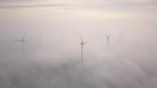 Wiatraki w mgle o wschodzie słońca. Turbiny wiatrowe z widoku z lotu ptaka. Zrównoważony rozwój, przyjazne dla środowiska. — Wideo stockowe