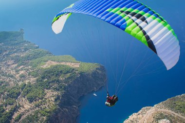Uçmayı hayal et. Yamaç paraşütü uçuyor. Üst te. Mavi gökyüzü ve deniz. 