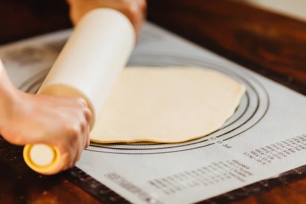 Female chef cook hands rolling dough with pin on silicone baking mat — Stock Photo, Image