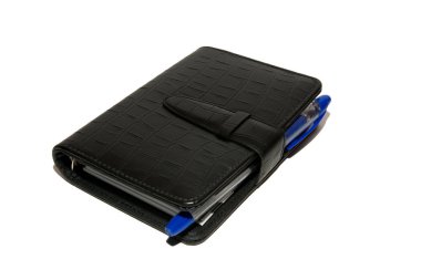 Siyah günlüğü mavi tükenmez kalem ile beyaz bir masada yatıyor. Günlüğü ve beyaz zemin üzerine kalem. İzole.