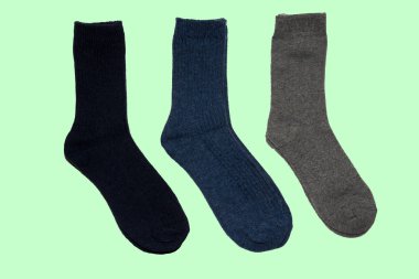 Three pairs of socks. Socks made of natural wool. Warm socks. Three pairs of colorful socks. On a green background. Isolated.