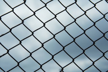 Siyah metal çit-kafes kafes bezi. Kasvetli bulutlu gri gökyüzü. Çitin arka plan görüntüsü.