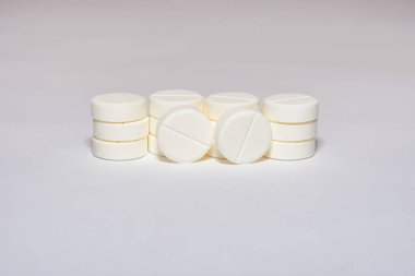 İlaçlar, vitaminler ya da takviyeler. Gri arka planda beyaz tabletlerin pürüzsüz yığını. Yumuşak seçici odak.