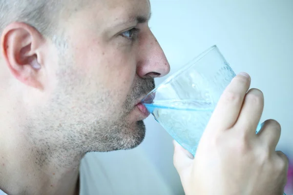 Manusia minum air dari gelas biru yang indah — Stok Foto