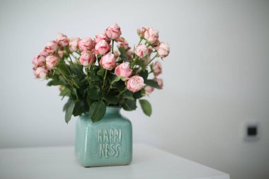Beautiful pastel pink roses in a shabby chic crackled vase with the word happiness on it clipart