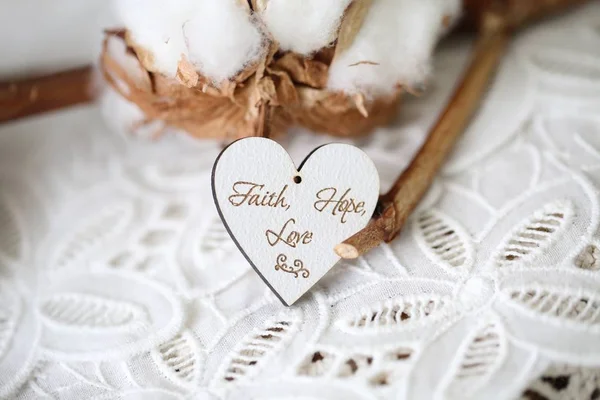 Wooden shaped heart with written words Faith, Hope, Love on it, vintage font