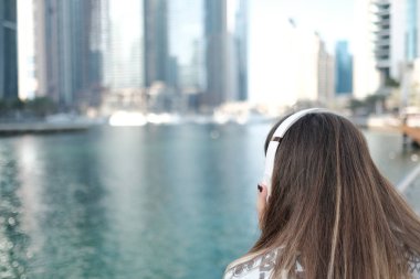 Genç kadın arıyor onun Merkez over büyük kulaklıklar ile su kanalı arkadan görüntülemek