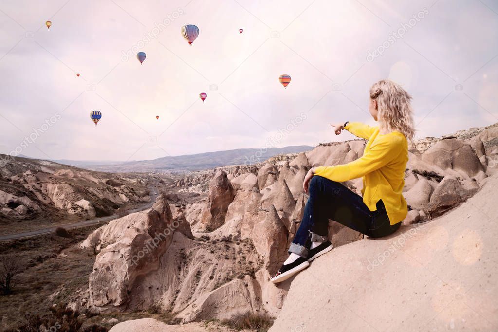 Young woman shows to the balloons in Cappadocia