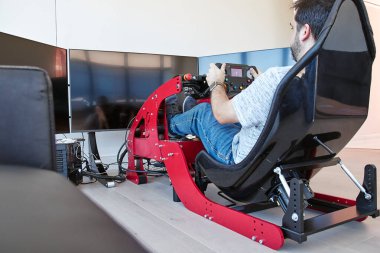 Kırmızı F1 sürücü simülatörü. Alttaki odadan beyaz odada 3 ekran var.