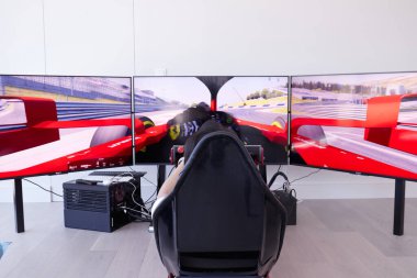 Kırmızı F1 sürücü simülatörü beyaz odada 3 ekran arkadan
