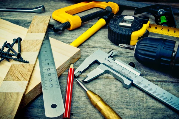 Tools on the wooden surface, still life. Screwdriver, scabbard, level, ruler, pencil, screws, core