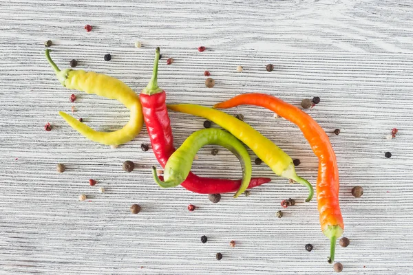 Chili pepper as well as bell pepper on a wooden background