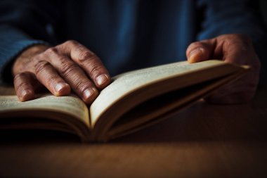 Açık bir kitap bir yaşlı adamın ellerini tutun