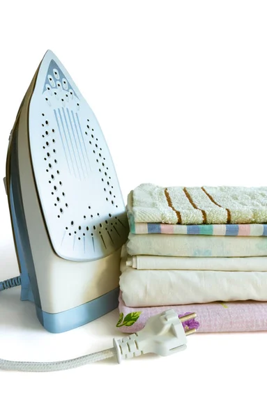 Electric iron and a stack of ironed clothes on a white background