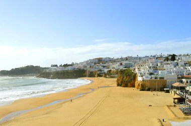 Portekiz 'deki Albufeira Sahili' nde bahar güneşinde yürüyen insanlar 