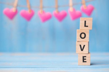 LOVE wooden cubes with pink heart shape decoration on blue table background and copy space for text. Love Romantic and Happy Valentines day holiday concept